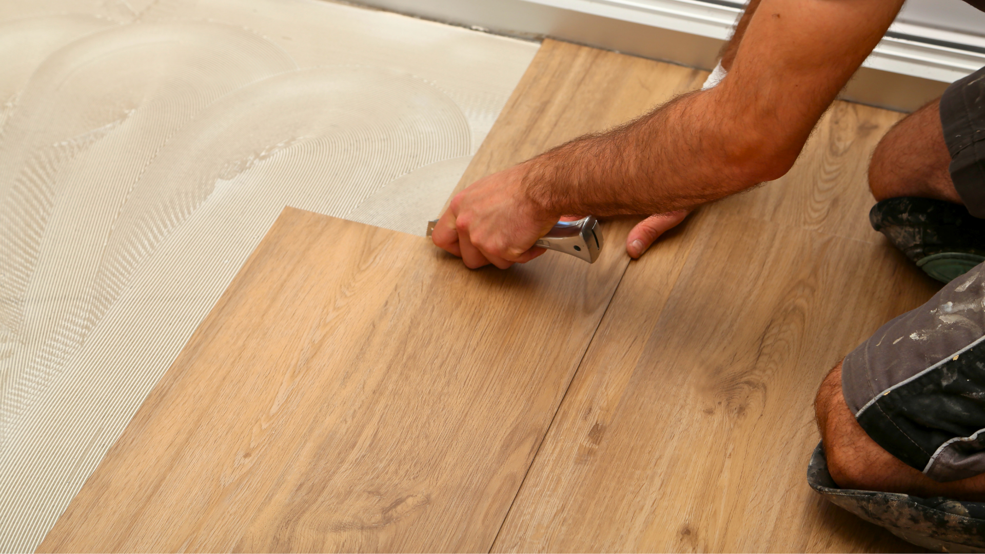 Worker installing glue down luxury vinyl flooring in Flint MI